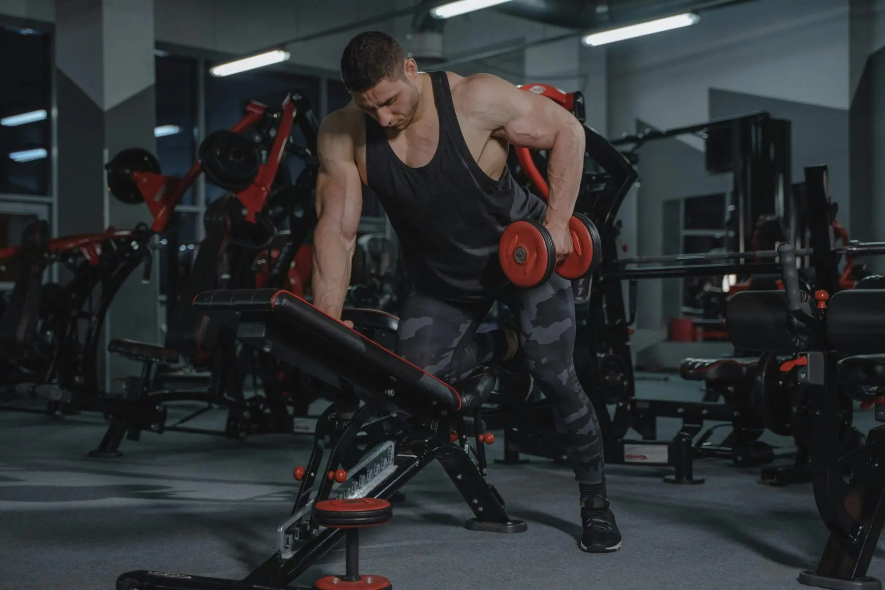 Personne en tenue de sport soulevant des poids lors d’un entraînement de musculation trois fois par semaine — séance fitness, force musculaire, routine régulière, musculation, corps tonique et bien-être