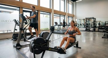 photorealistic wide shot inside a modern professional gym in the foreground a 3976 Rameur ou vélo elliptique: le comparatif pour vos objectifs