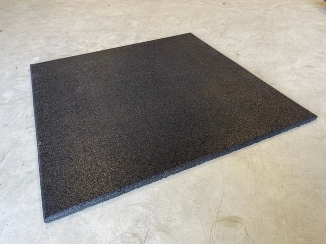 Dalle de sol en caoutchouc noire, texture granuleuse, sur béton.