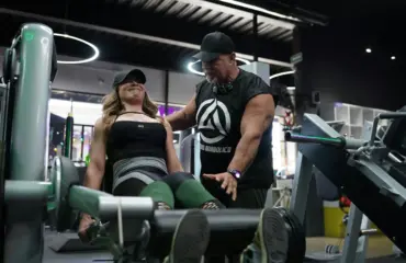 musculation et programmes d’entraînement Femme s'entraînant sur une machine de gym avec un entraîneur.