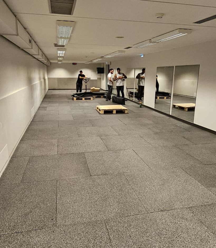 Trois hommes travaillant dans une salle vide avec miroirs.