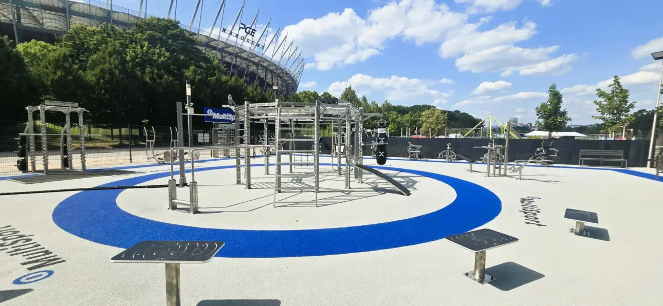 Parc de fitness extérieur moderne sous ciel bleu près d'un stade.