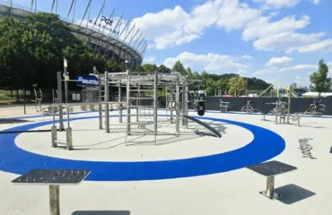 matériel de musculation et de fitness outdoor en inox pour collectivités, clubs et espaces d’entraînement extérieurs Parc de fitness extérieur moderne sous ciel bleu près d'un stade.