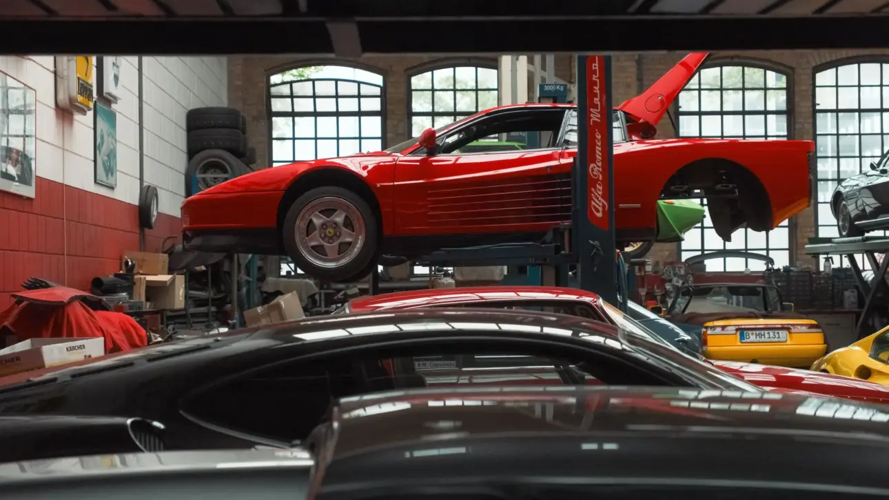 Ferrari Testarossa rouge en réparation dans un garage spécialisé.
