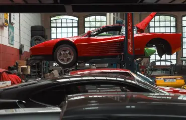 Ferrari Testarossa rouge en réparation dans un garage spécialisé.