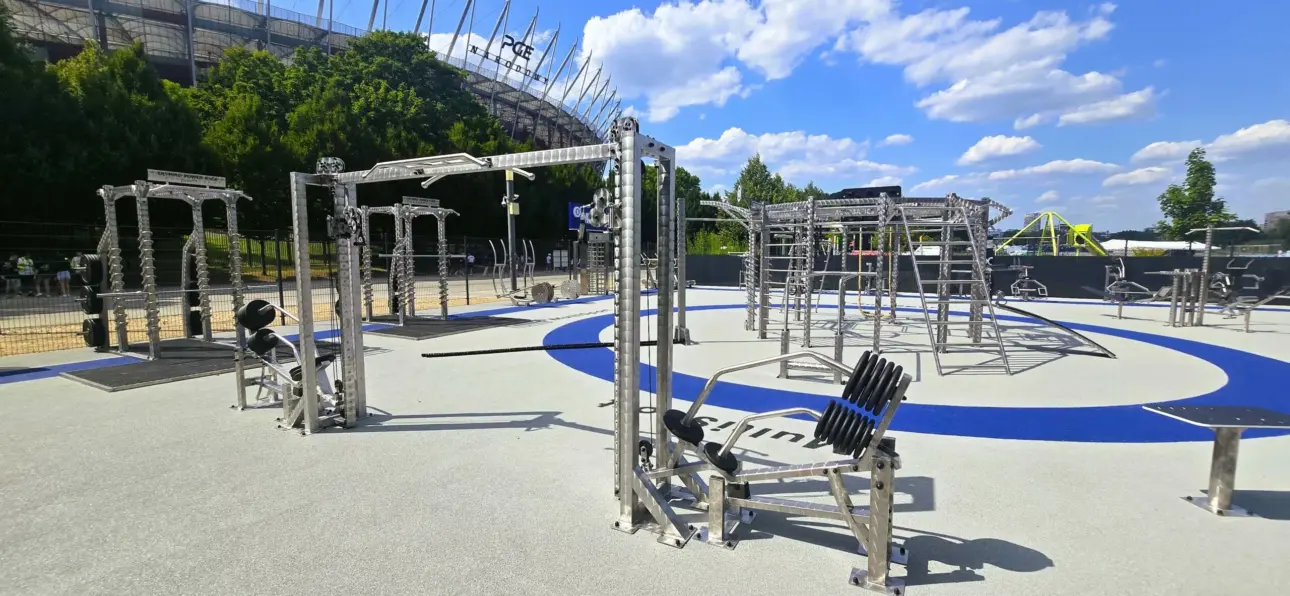 Parc de fitness extérieur moderne avec équipements devant un stade.