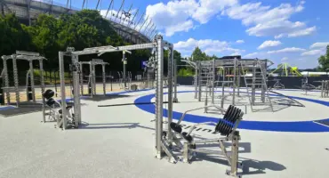 Parc de fitness extérieur moderne avec équipements devant un stade.
