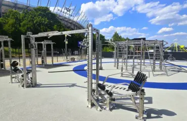 Parc de fitness extérieur moderne avec équipements devant un stade.
