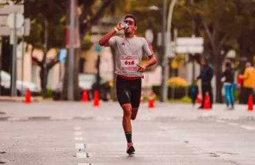 Coureur buvant, eau éclaboussant, course sur route mouillée, effort.