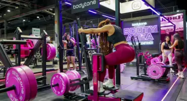 Femmes s'entraînant dans une salle de sport avec des appareils roses Bodytone.