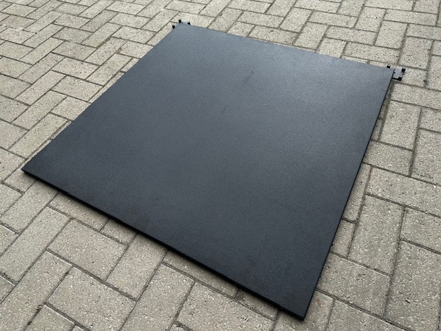 Panneau noir texturé sur pavés gris en motif chevrons.