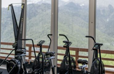 Équipement de gym (rameur, vélos) avec vue sur les montagnes.