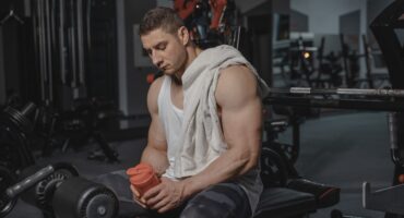 Homme musclé au repos en salle de sport, tenant un shaker.