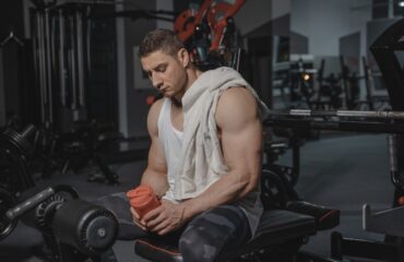 Homme musclé au repos en salle de sport, tenant un shaker.