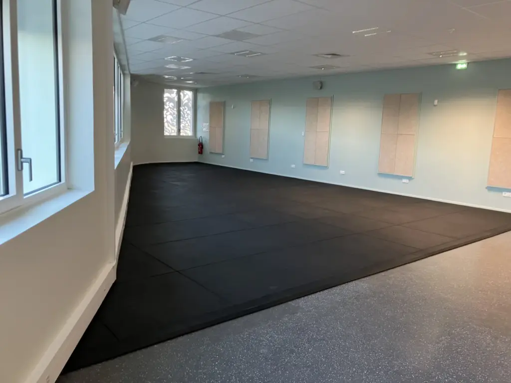Sol en dalles caoutchouc noires dans une salle vide, juste après la pose