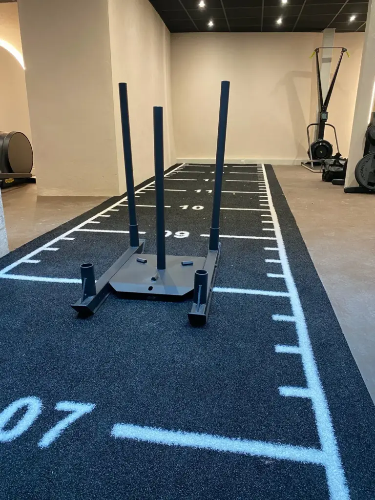 Traîneau de poussée sur une piste en gazon synthétique noire graduée, en salle